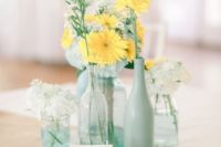 23 a rustic centerpiece with doilies, clear glass vases and mint bottles plus white and yellow blooms