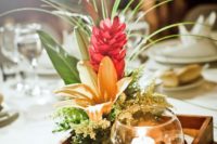 23 a tropical beach centerpiece with a box of sand, a candle and some tropical blooms