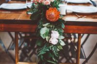 24 a lush organic table runner of greenery, blush blooms and king proteas that look very tropical-like