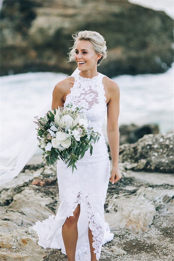 a white lace sheath wedding dress with an illusion neckline and a front slit for a sexy look