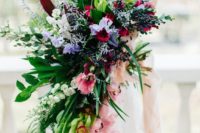 26 a romantic cascading wedding bouquet with pink, purple and red blooms plus much greenery