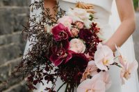a bold cascading wedding bouquet of purple poenies and orchids, blush orchids and greenery and neutral roses