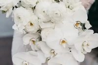 a cascading white wedding bouquet composed of ranunculus and orchids looks very sophisticated