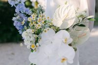a catchy wedding bouquet of blue blooms, white hydrangeas, chamomiles, orchids and anthurium is a cool idea