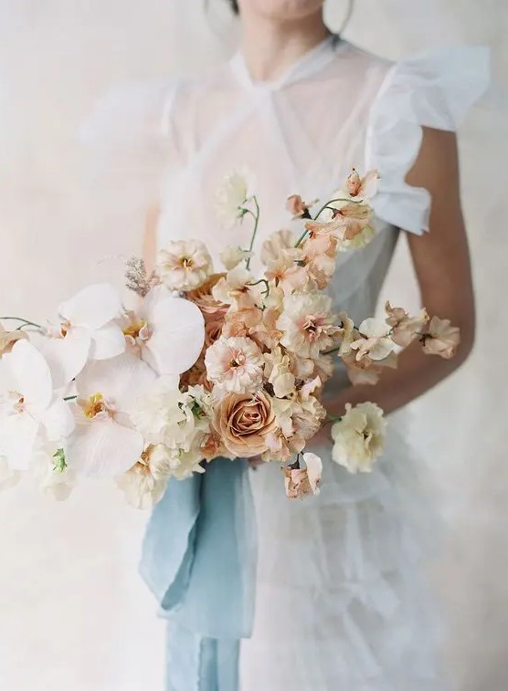 a chic and beautiful wedding bouquet of sweet peas, some other blooms and blush orchids is an exquisite statement