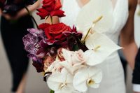 a color block wedding bouquet of burgundy and red roses, purple and white orchids, blush roses is wow