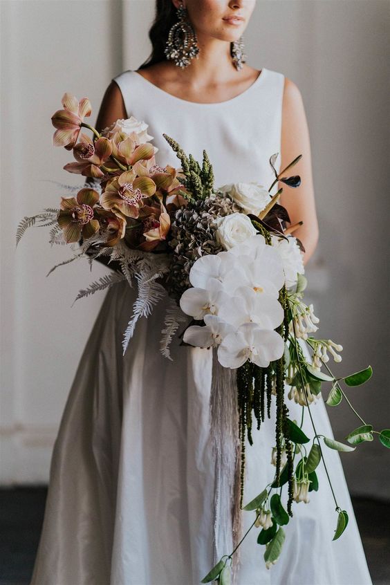 a color block wedding bouquet with rust and white orchids, greenery and dried leaves is a stylish and catchy idea