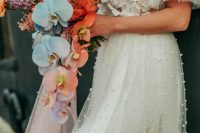a colorful cascading wedding bouquet of lilac, orange blooms and smoke bush and aqua and orange orchids