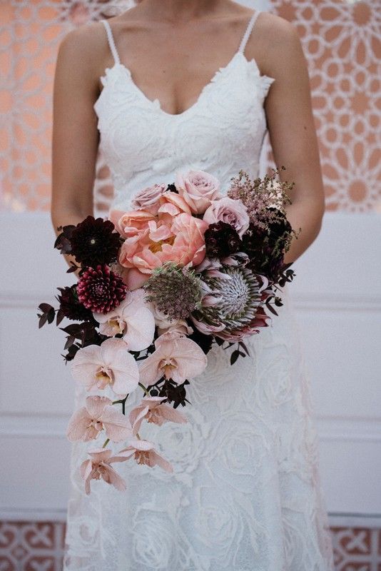a contrasting wedding bouquet of peachy peonies, blush roses and orchids, deep purple dahlias is a chic idea