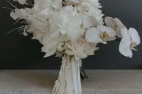 a dreamy and ethereal white wedding bouquet of roses, orchids, lunaria, dried grasses and twigs and white amaranthus
