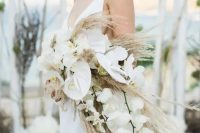a dreamy cascading boho wedding bouquet of white orchids and pampas grass is a cool idea for a modenr boho bride