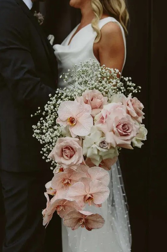 a gorgeous cascading wedding bouquet with blush roses and orchids, white roses and baby's breath is a beautiful idea to rock