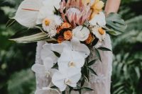 a gorgeous tropical wedding bouquet of white orchids, white roses and daisies, yellow blooms, a king protea and anthurium and greenery