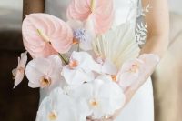 a lovely modern wedding bouquet of white orchids, blush anthurium, fronds and grasses is a cool and bold solution