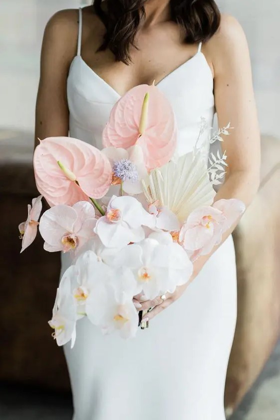a lovely modern wedding bouquet of white orchids, blush anthurium, fronds and grasses is a cool and bold solution