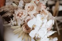 a lovely neutral wedding bouquet of dusty pink roses, white orchids, lunaria, pampas grass and fronds is chic
