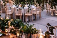 a lovely woodland wedding centerpiece of moss, greenery, potted plants and candles is a stylish solution