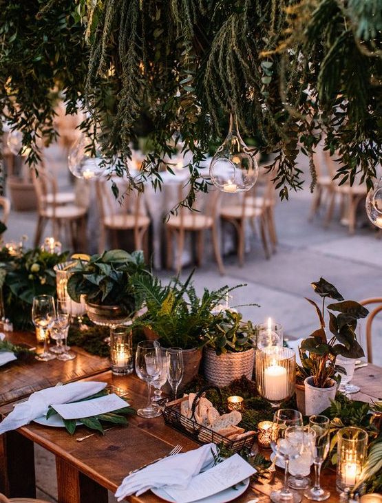 a lovely woodland wedding centerpiece of moss, greenery, potted plants and candles is a stylish solution
