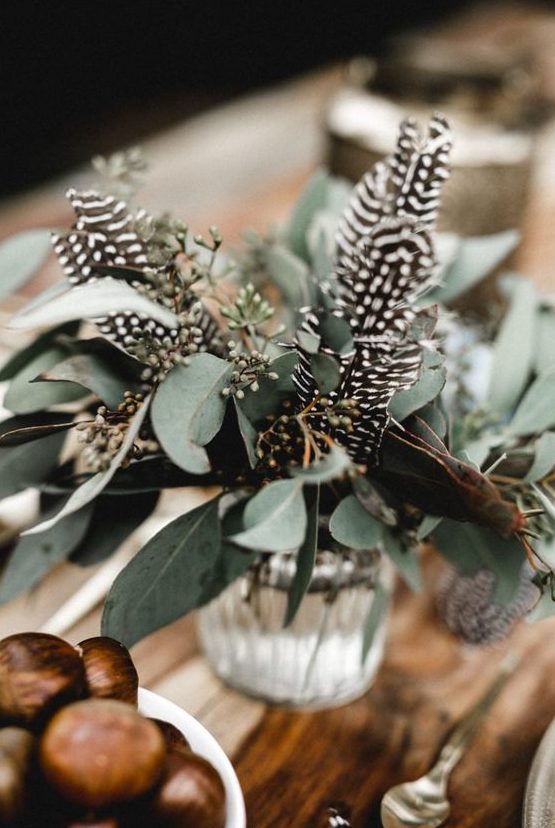 a natural boho wedding centerpiece of eucalyptus and feathers is a beautiful idea