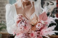 a pink wedding bouquet of pink and peachy roses, pink fronds, cascading pink orchids and pampas grass