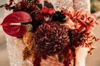 a refined burgundy wedding bouquet of hydrangeas, orchids, anthuriums, bold leaves and amaranthus for the fall