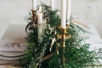 a simple winter wedding centerpiece of evergreens, little blooms and candles in candle holders for a Nordic wedding