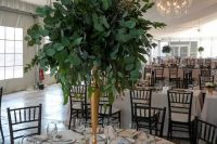 a tall foliage centerpiece with myrtle, seeded and silver dollar eucalyptus in a brass vase