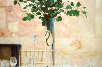 a tall silver eucalyptus centerpiece in a clear vase is an ultra-modern idea of wedding decor
