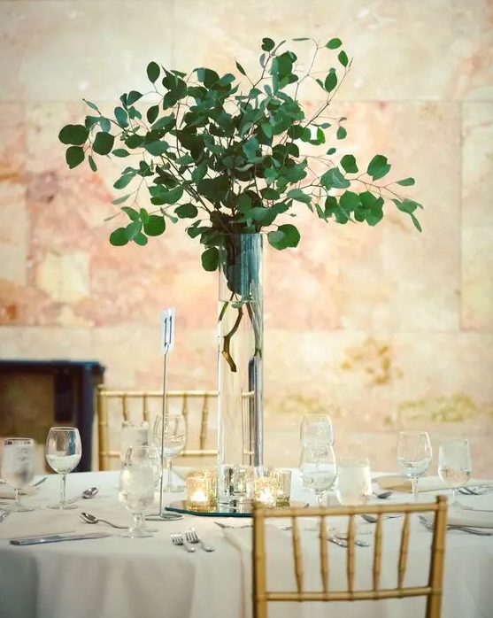 A tall silver eucalyptus centerpiece in a clear vase is an ultra modern idea of wedding decor