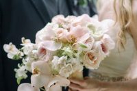 a wedding bouquet of some white blooms, blush roses and orchids is a stylish and tender arrangement