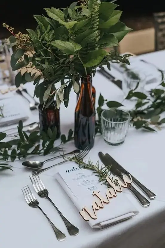 dark bottles with lush greenery and a greenery table runner will refresh any backyard wedding tablescape