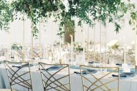 stylish modern wedding centerpiece of lush cascading greneery on tall gold stands
