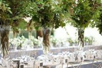 such tall lush textural greenery centerpieces in clear vases create a feeling of outdoors right in your venue