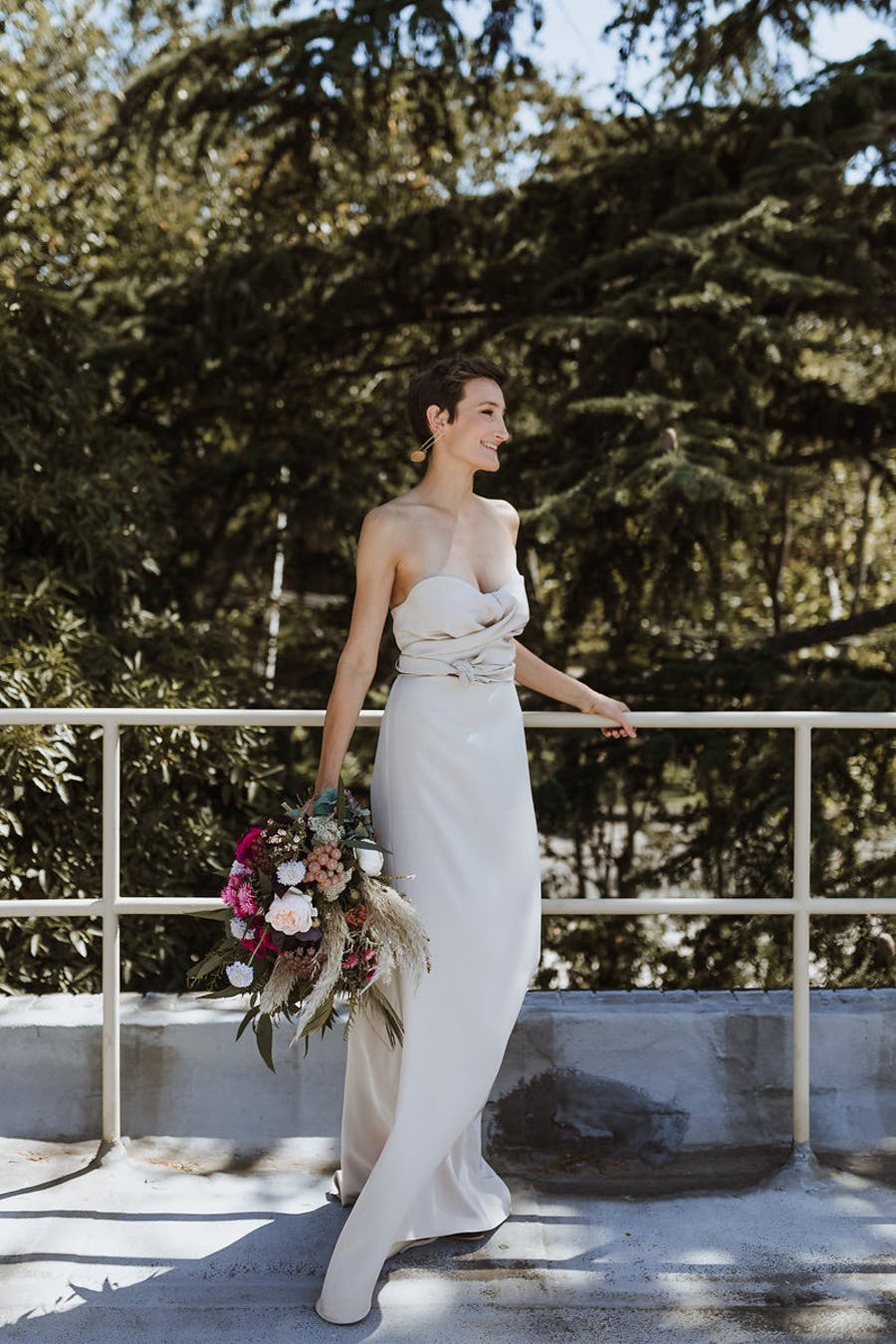 One of the brides was wearing a strapless sheath wedding dress with a draped bodice and statement earrings