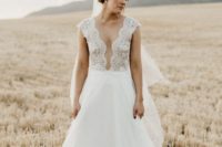 02 The bride was wearing a gorgeous A-line wedding dress with a lace bodice, an illusion plunging neckline, cap sleeves and a layered skirt