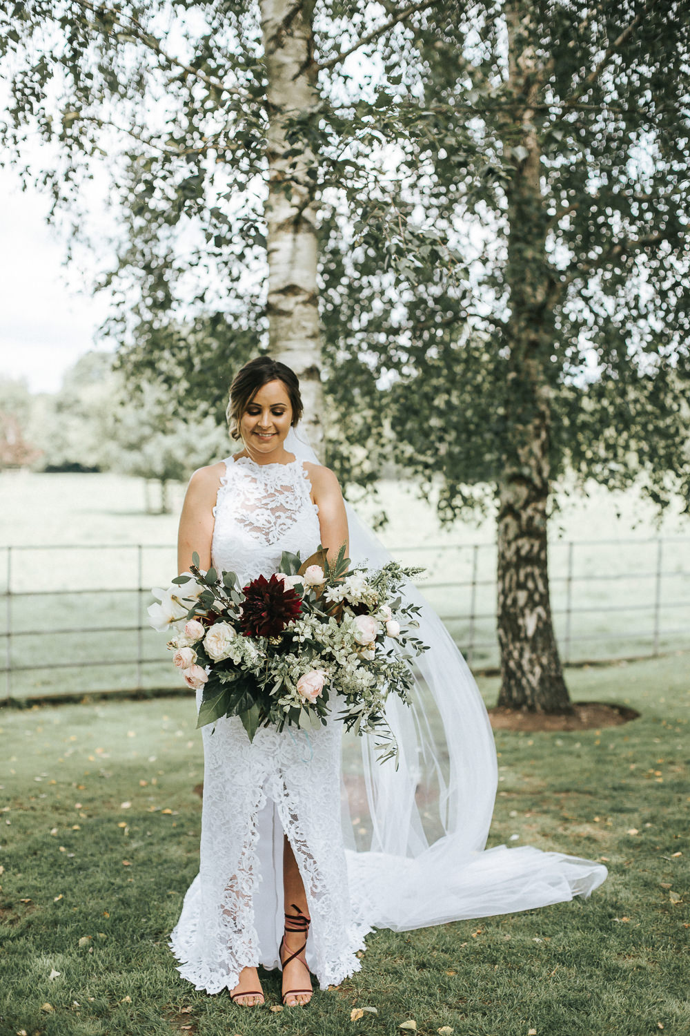 The bride was wearing a lace sheath dress with an illusion halter neckline and a front slit