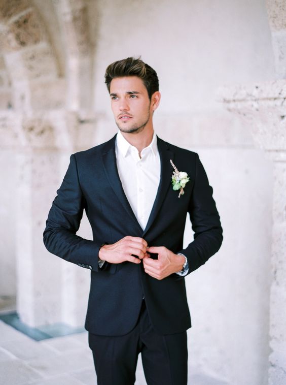 a black groom's suit with a white shirt and a boutonniere is a timeless and effortlessly chic look
