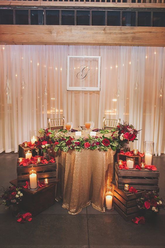 a sweetheart table decorated with crates with flower petals and candles on them for a romantic touch