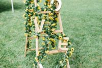 05 a ladder decorated with wooden letters and sunflowers and greenery for a summer wedding