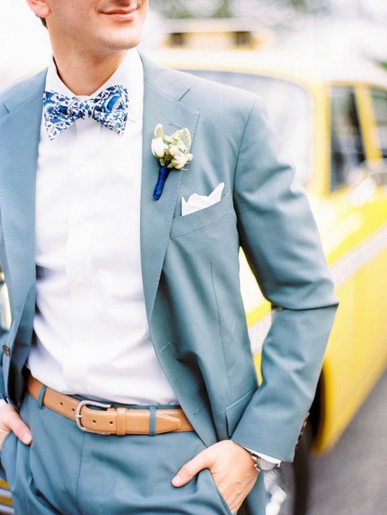 a light blue suit, a bold printed blue bow tie, a light brown belt for a cheerful summer look