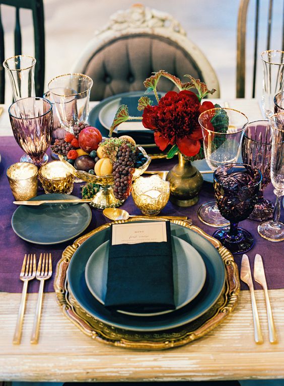 a decadent jewel tone tablescape with a deep purple table runner, purple goblets, gold flatware and a gold charger