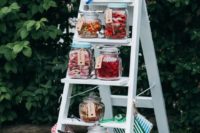 12 a candy table of a ladder and jars with all kinds of candies and frames