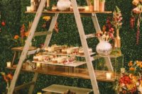 13 a dessert table designed of a ladder and shelves plus clear glass stands and gold vases and pots for a glam feel