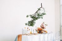 16 a modern tablescape done in orange and burgundy plus light blue and a green branch over the table