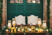 16 a wow sweetheart table with gold and greeneyr, candles and an emerald door behind it