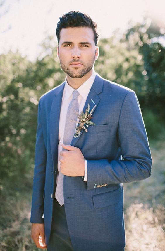a blue suit with a light blue tie and a herby boutonniere for a romantic and chic look