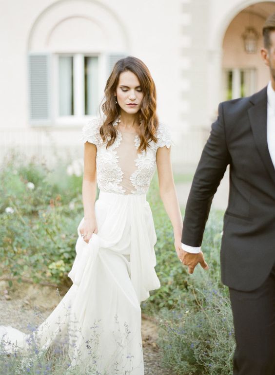 a modern A line gown with a lace bodice with a covered plunging neckline and short sleeves plus a plain pleated skirt