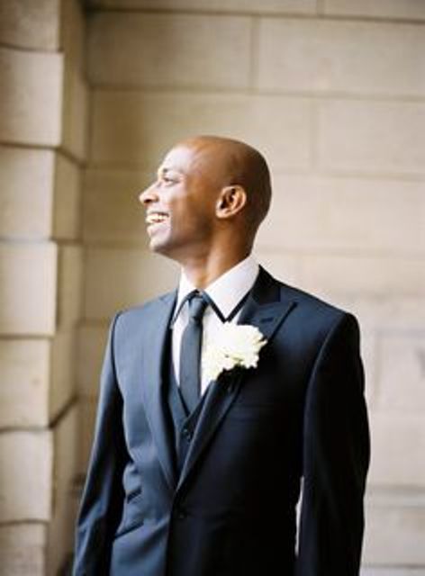 a modern black tuxedo with a vest, a blakc tie and a black rimmer collar for a personalized touch