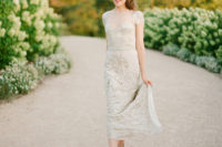 21 a sheath embellished wedding dress with an illusion neckline, short sleeves and a sparkly sash for a glam bride