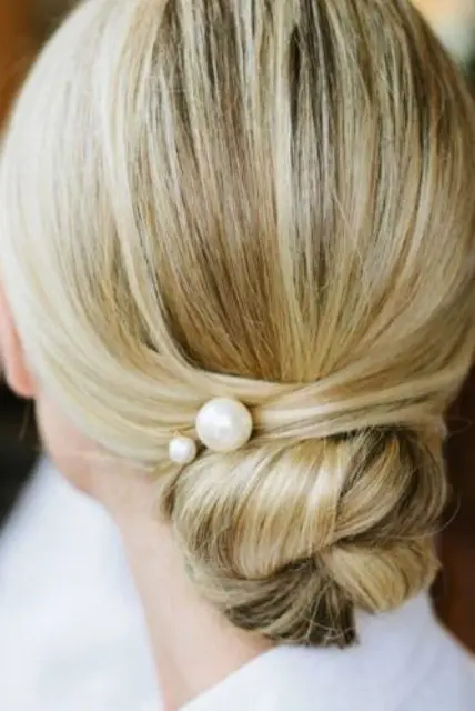 a super elegnat low twisted bun with a couple of large pearl pins for a timeless look